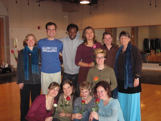 students holding roses at graduation, together with instructors